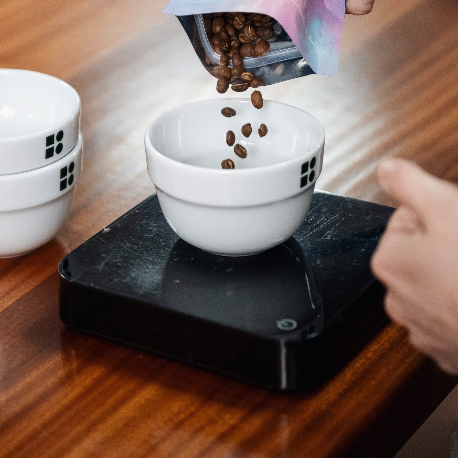 beans being poured into a cupping bowl ontop of the acaia scales