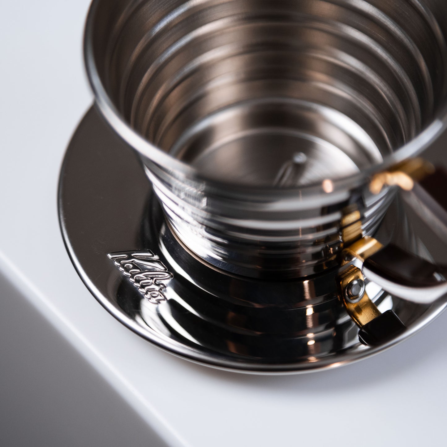 stainless steel kalita dripper on a white surface