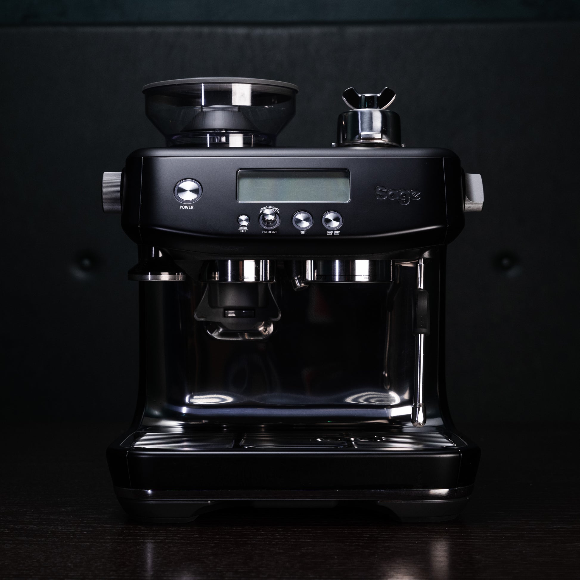 a dark image of the back sage barista pro machine, set against a dark background that really highlights the sliver and steel buttons and valves