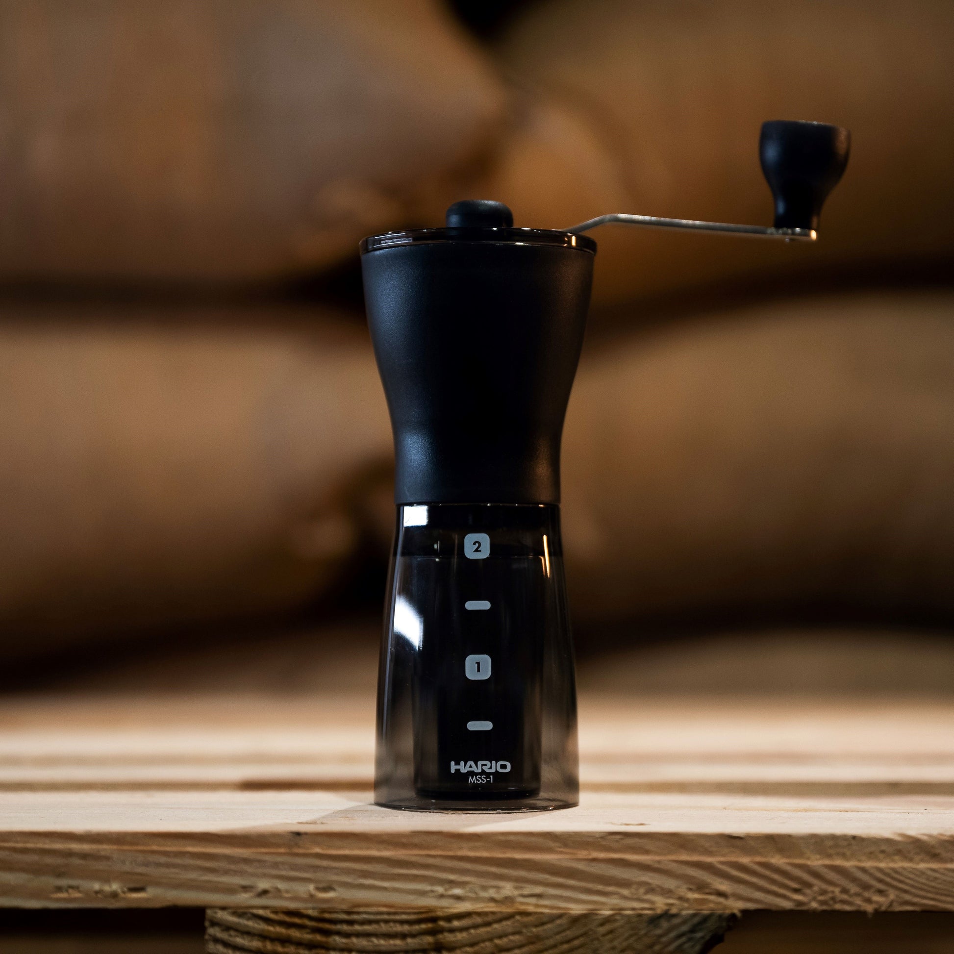 hario coffee grinder in black set against greeb bean coffee bags 